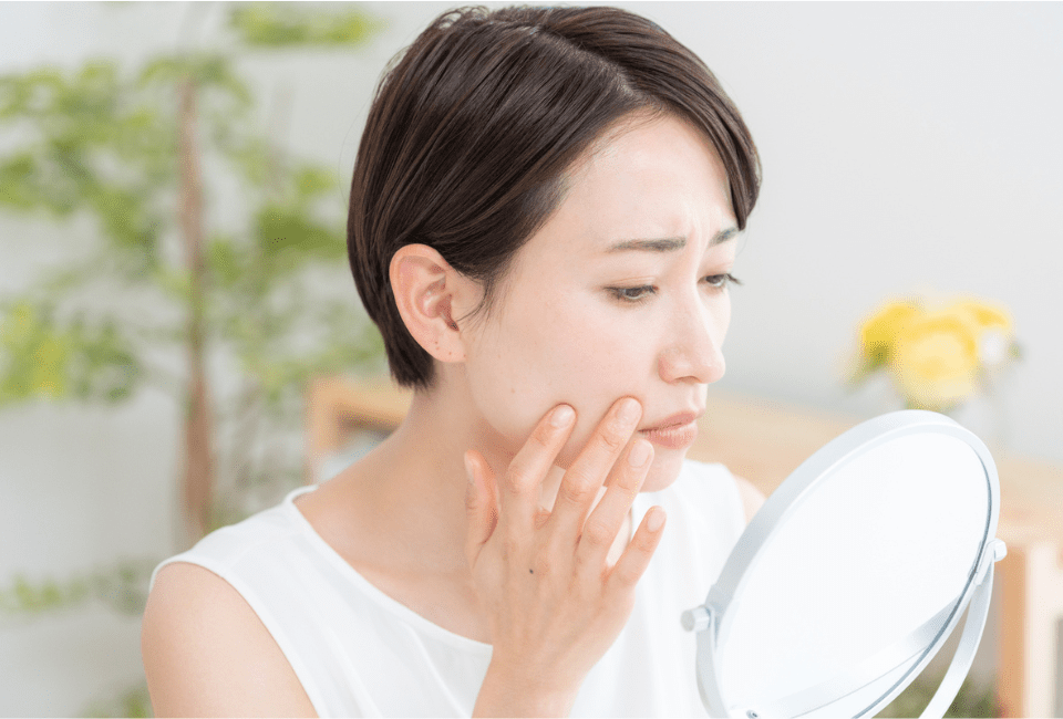 鏡で肌を見る女性